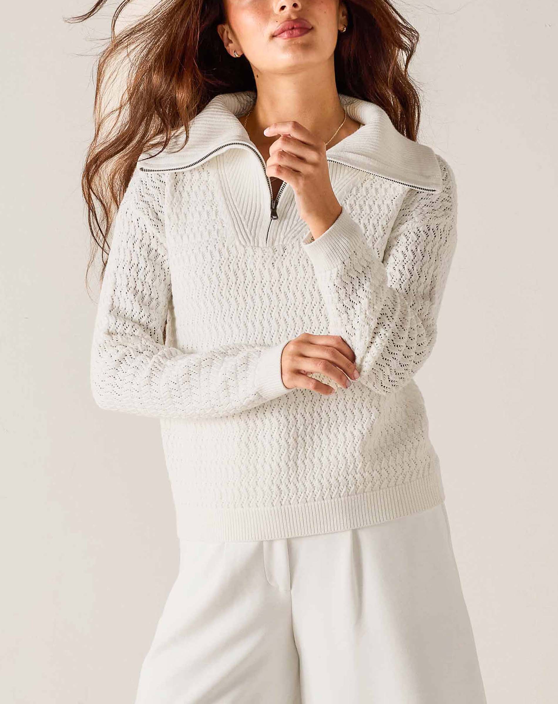 Woman wearing a textured white sweater against a plain background