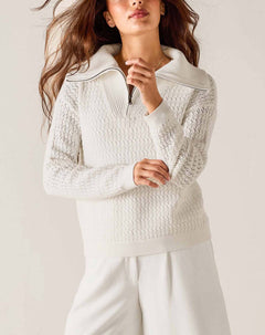 Woman wearing a textured white sweater against a plain background