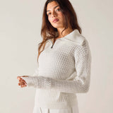 Woman wearing a textured white sweater against a plain background