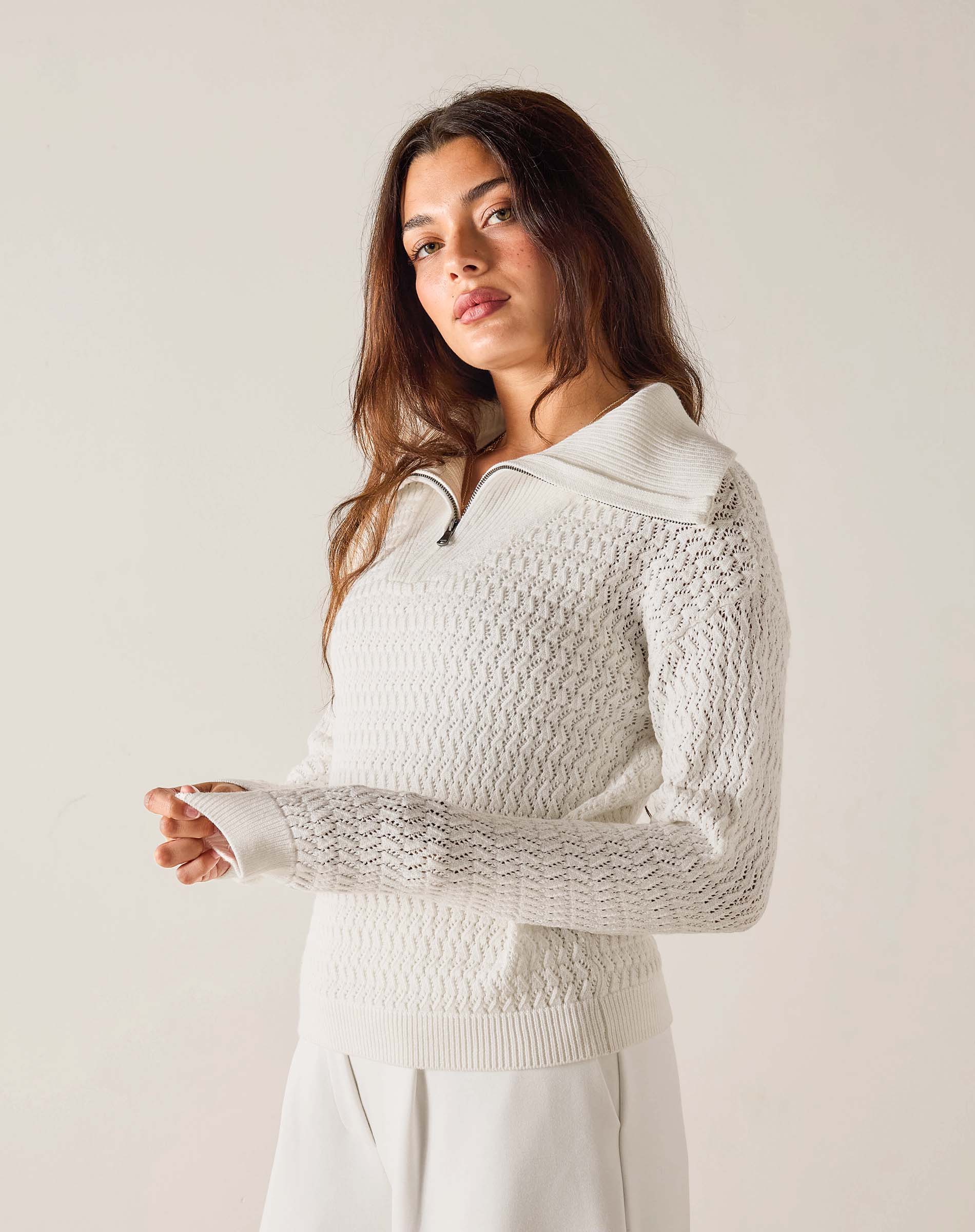 Woman wearing a textured white sweater against a plain background