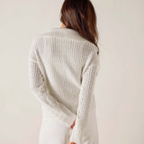 Woman wearing a textured white cardigan against a plain background