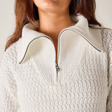 Close-up of a person wearing a white knit sweater with a quarter zip.