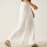 Person wearing white pants and sneakers on a plain background
