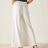 Person wearing white wide-leg pants with a plain background