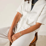 Person wearing a white outfit sitting on a chair with a neutral background