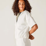 Woman wearing a white outfit against a plain background