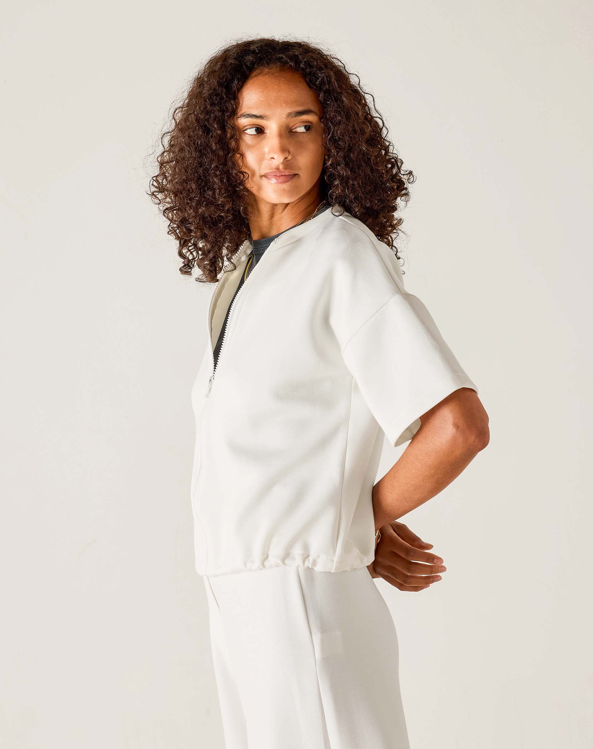 Woman wearing a white outfit against a plain background
