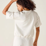 Person wearing a white satin top and pants against a plain background