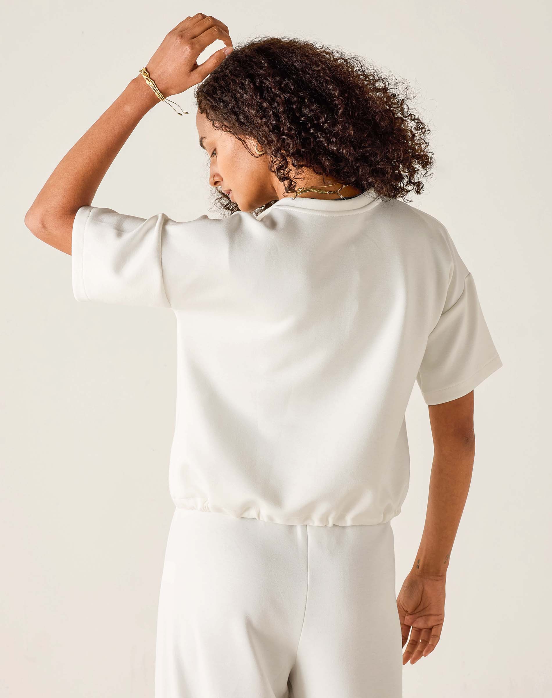 Person wearing a white satin top and pants against a plain background