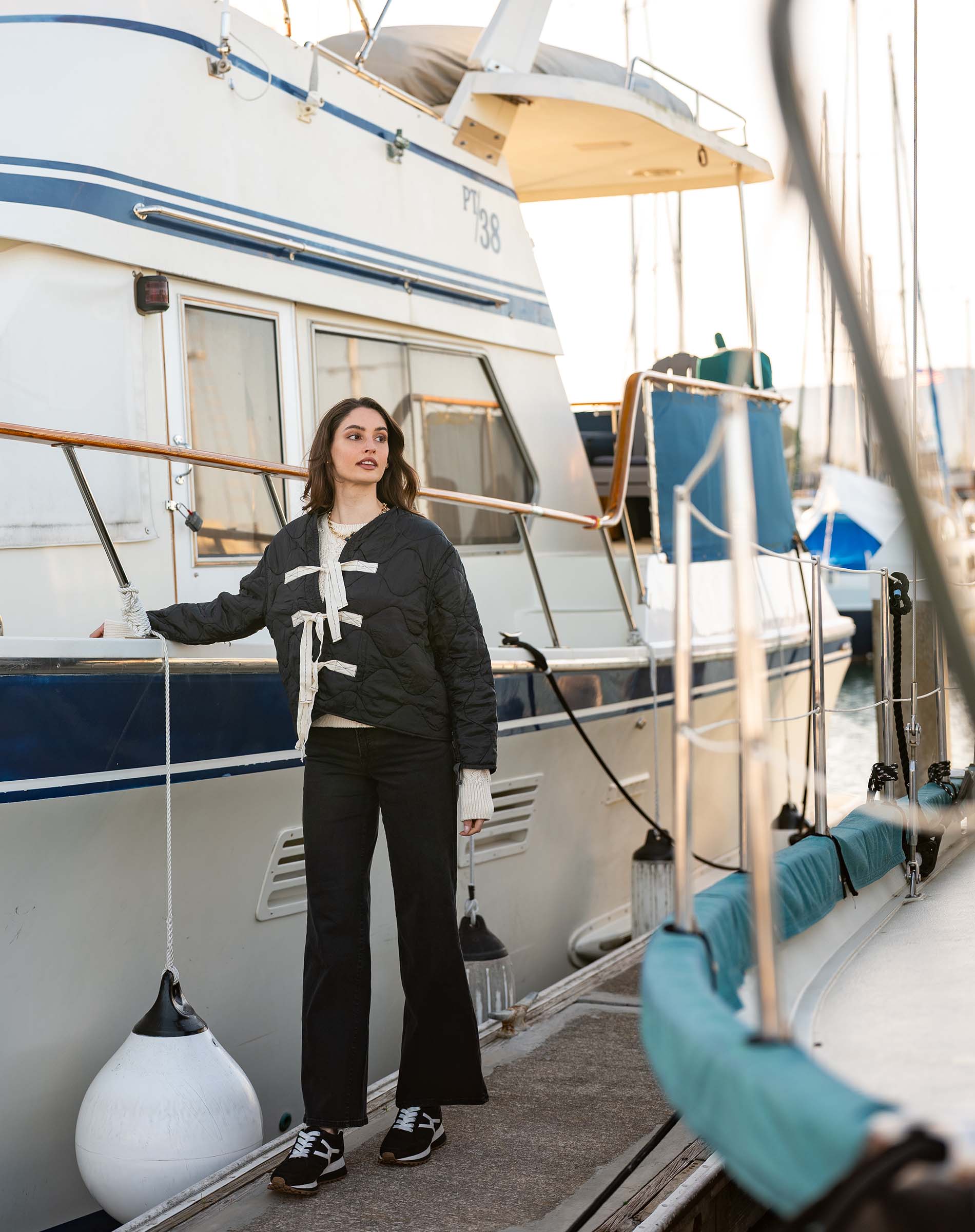Woman standing on a boat deck with a white and blue striped boat in the background
