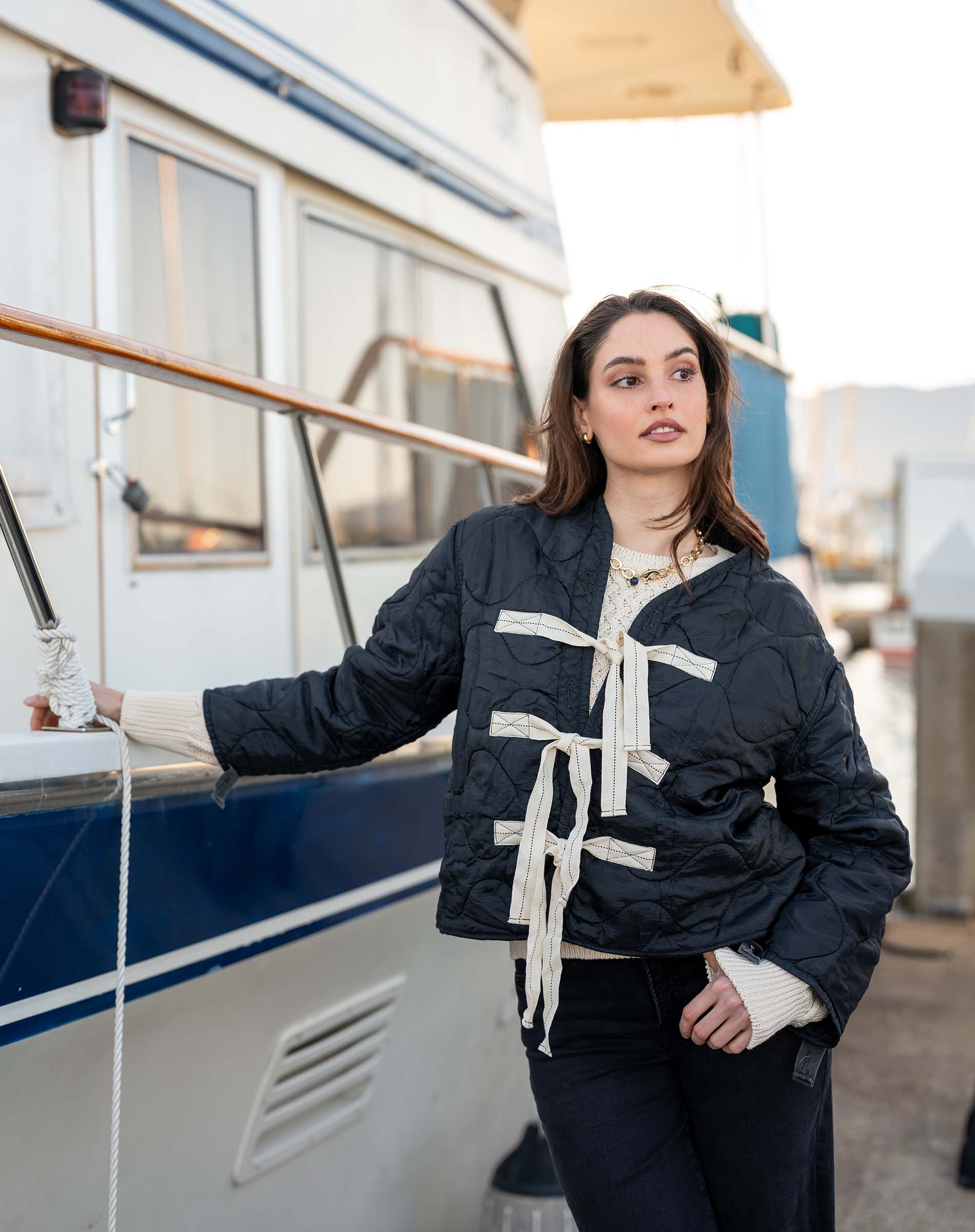 Woman wearing a navy blue jacket with white accents near a boat