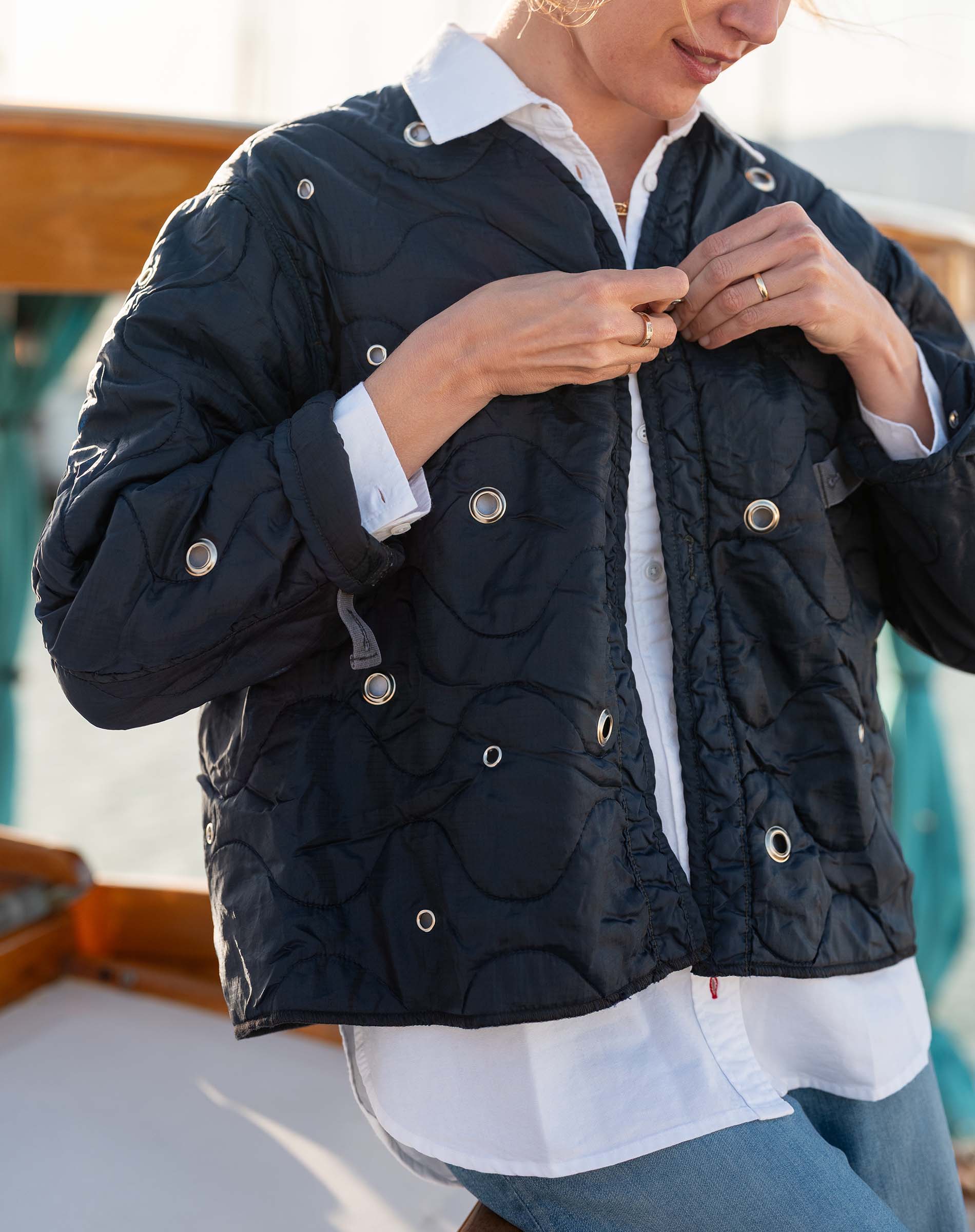 Person wearing a black quilted jacket with a blurred background
