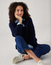 woman showcasing mersea sol mate crewneck pullover in navy sitting cross legged