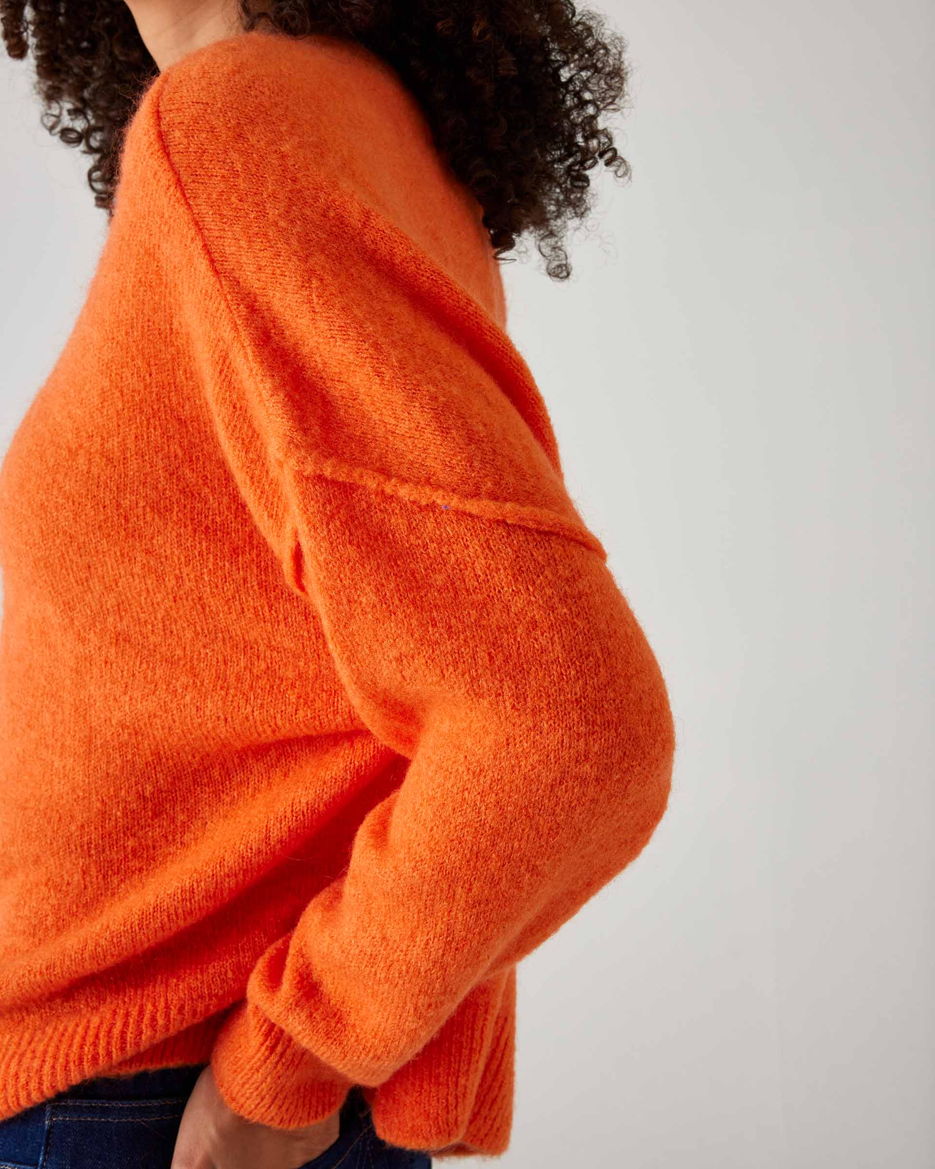 closeup of side of woman showcasing mersea sol mate crewneck pullover in tangerine