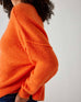 closeup of side of woman showcasing mersea sol mate crewneck pullover in tangerine