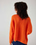 rearview of woman showcasing mersea sol mate crewneck pullover in tangerine