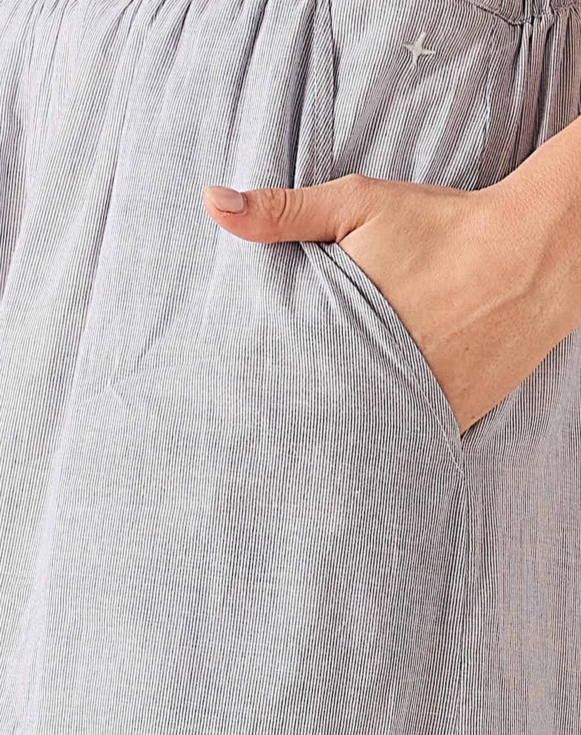Person wearing a gray striped shirt with a hand in the pocket