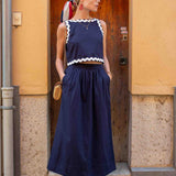 Woman wearing a navy blue dress with white trim standing in front of a wooden door.