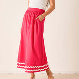 Person wearing a white top and red skirt with white trim on a plain background