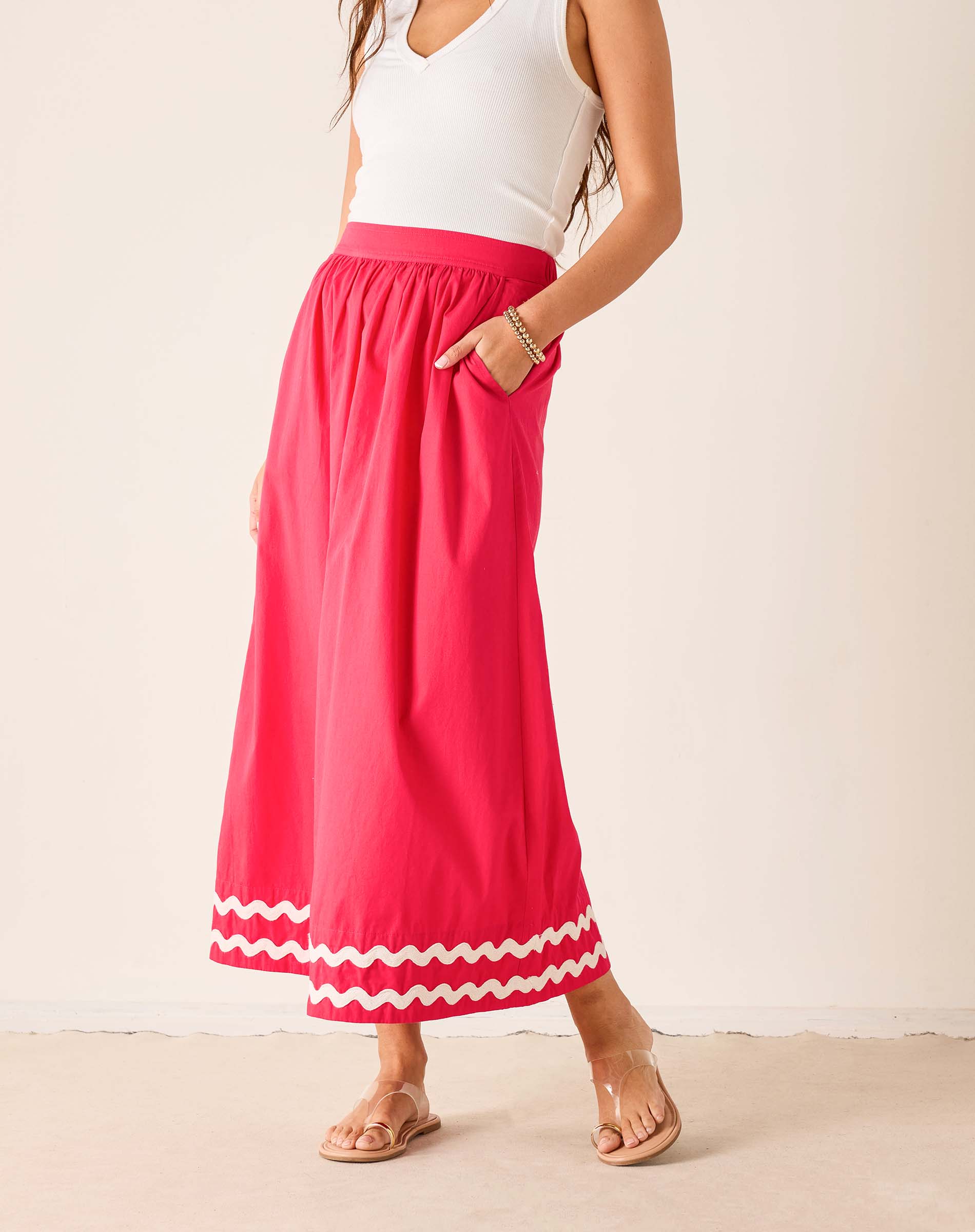 Person wearing a white top and red skirt with white trim on a plain background