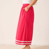 Person wearing a bright pink skirt with white trim on a plain background