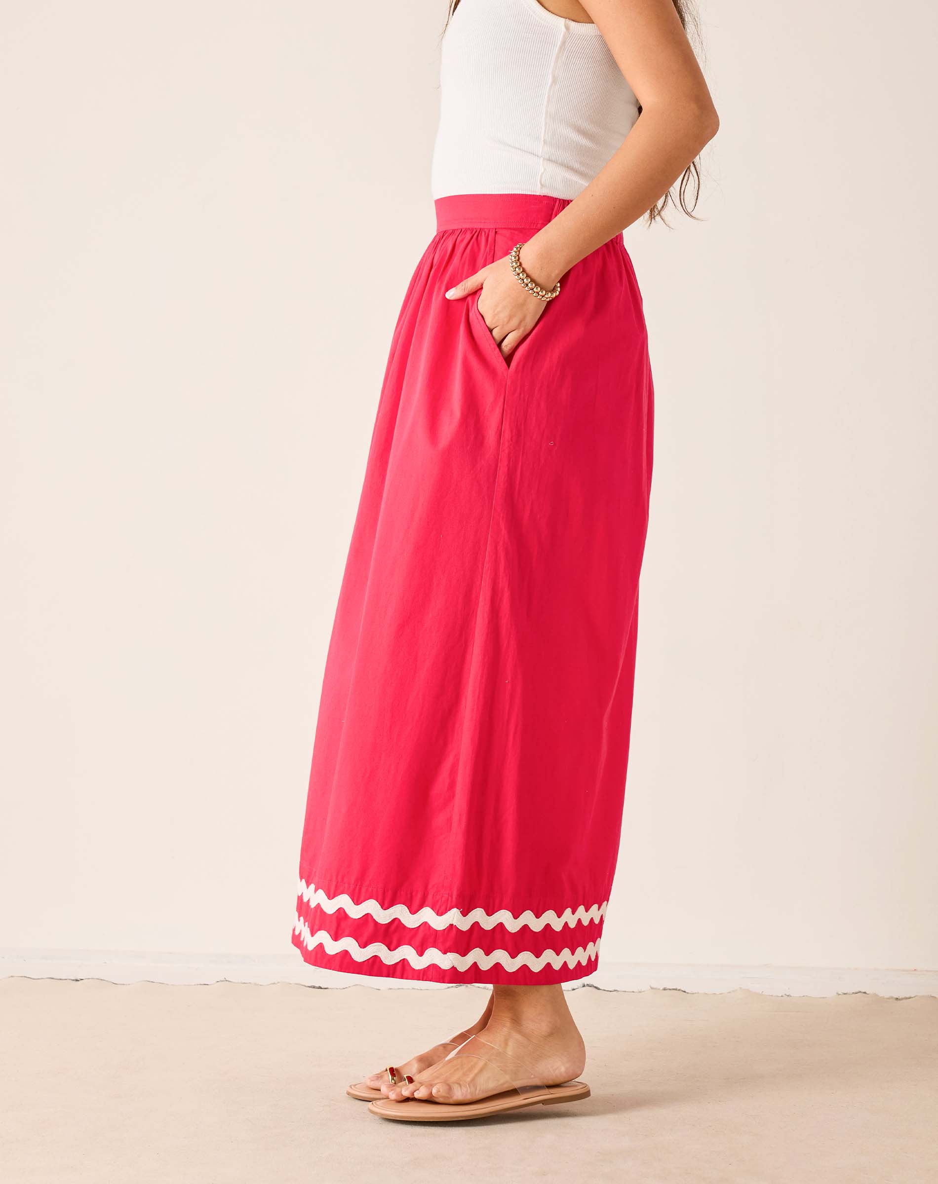 Person wearing a bright pink skirt with white trim on a plain background