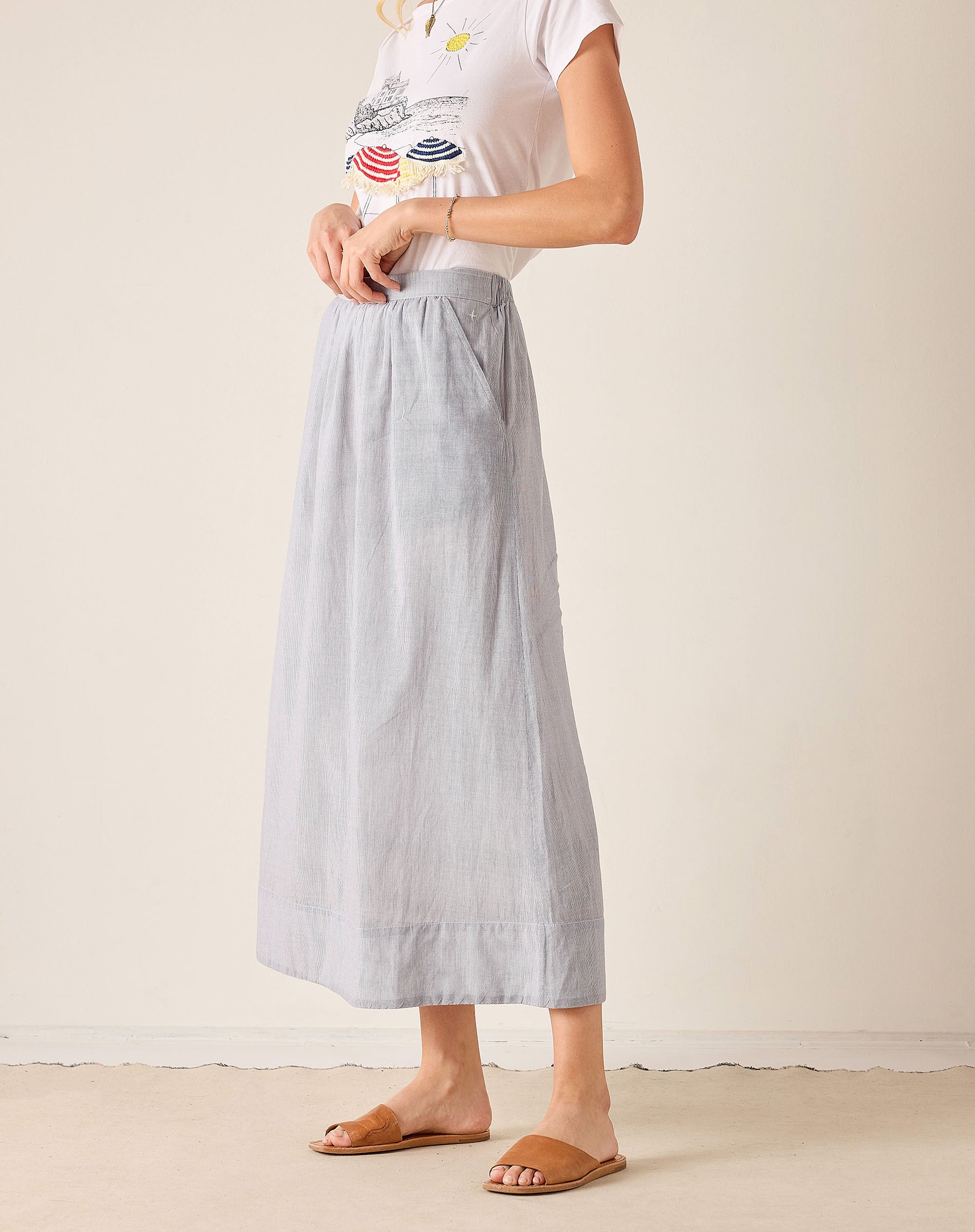 Woman wearing a white top and light blue skirt on a plain background