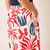 Person wearing a skirt with red and blue abstract pattern on a plain background