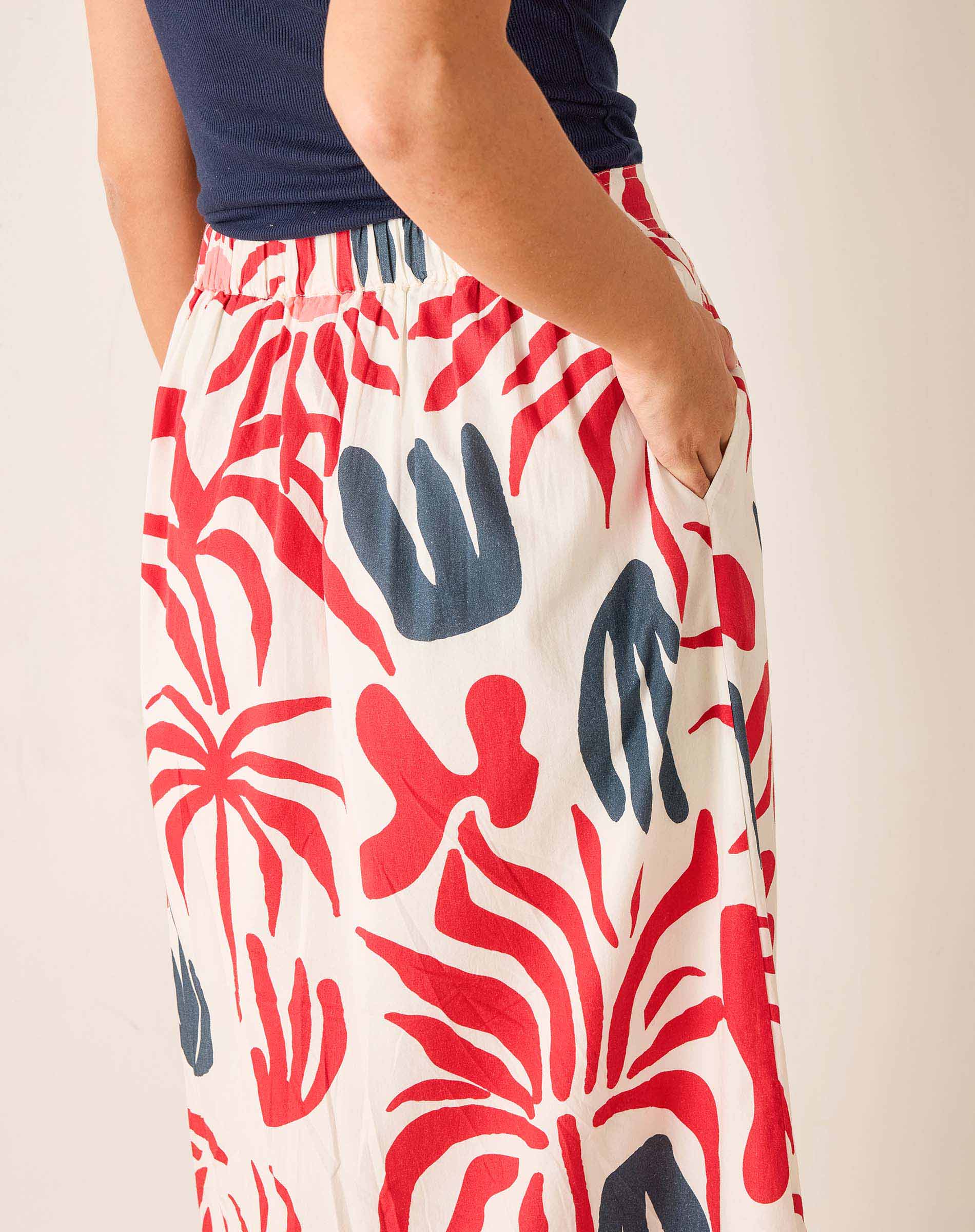 Person wearing a skirt with red and blue abstract pattern on a plain background