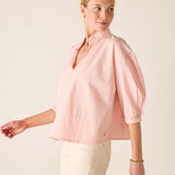 Woman wearing a light pink blouse against a plain background