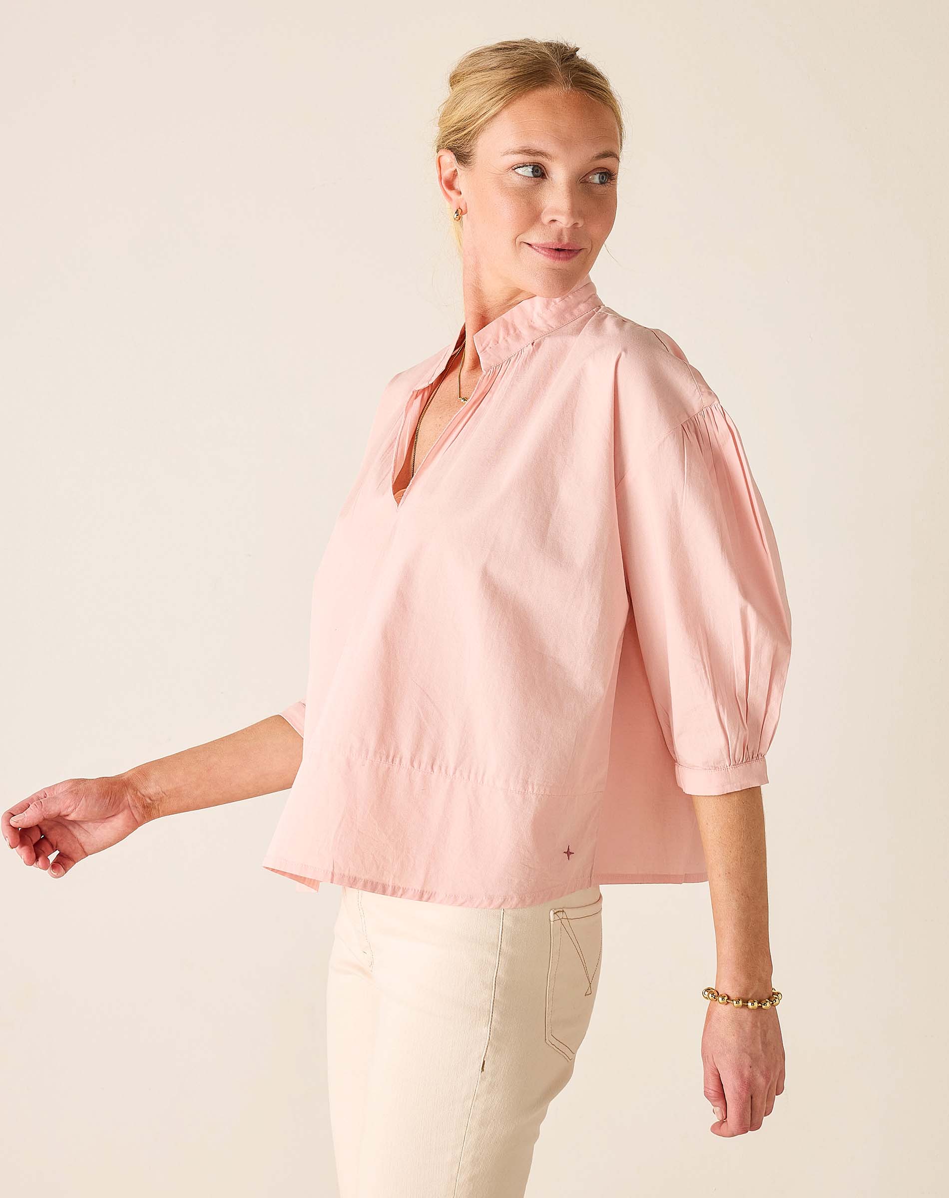 Woman wearing a light pink blouse against a plain background