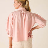 Woman wearing a light pink blouse with a neutral background