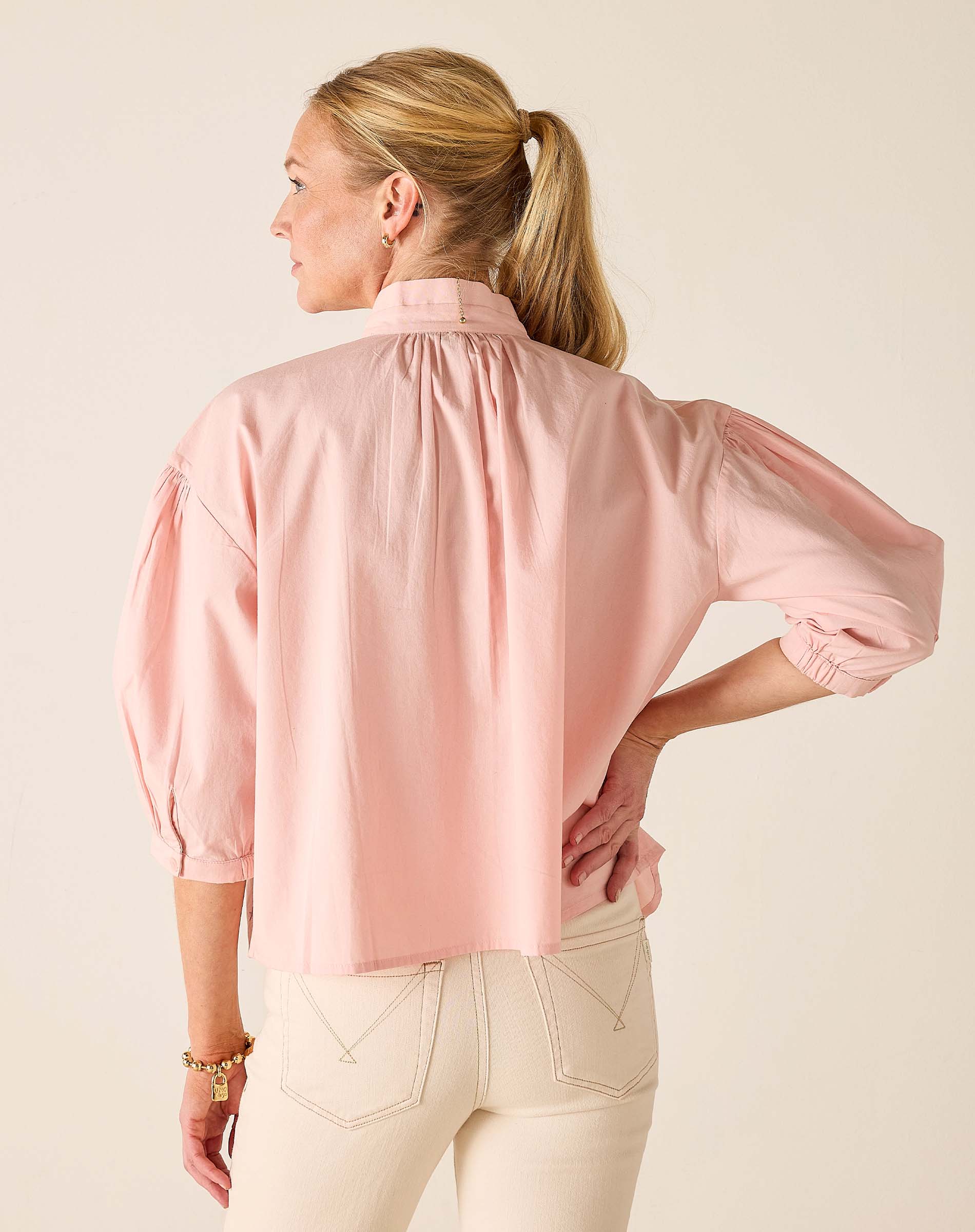 Woman wearing a light pink blouse with a neutral background