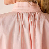 Close-up of a person wearing a light pink blouse with a neutral background