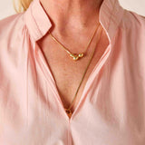 Person wearing a gold necklace with a pink shirt