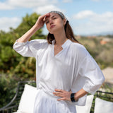 Woman in a white outfit standing outdoors with a scenic background