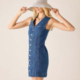 Woman wearing a blue denim dress and a wide-brimmed hat on a beige background