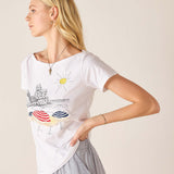 Woman wearing a white t-shirt with a colorful graphic design on a beige background