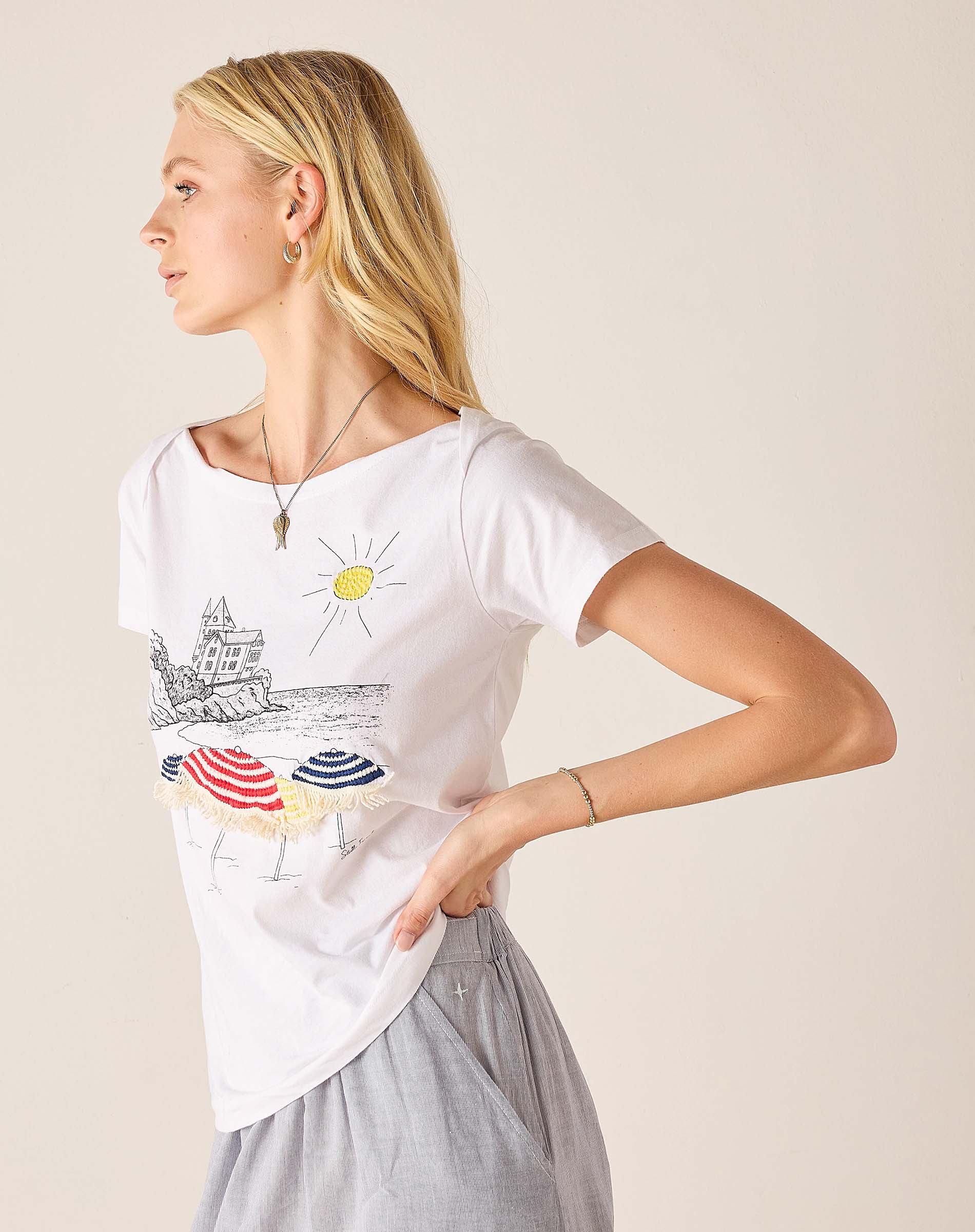 Woman wearing a white t-shirt with a colorful graphic design on a beige background