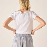 Person wearing a white t-shirt and light gray checkered pants against a beige background