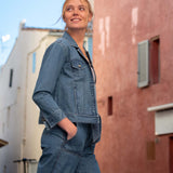 Woman wearing a denim outfit standing in an urban alleyway.