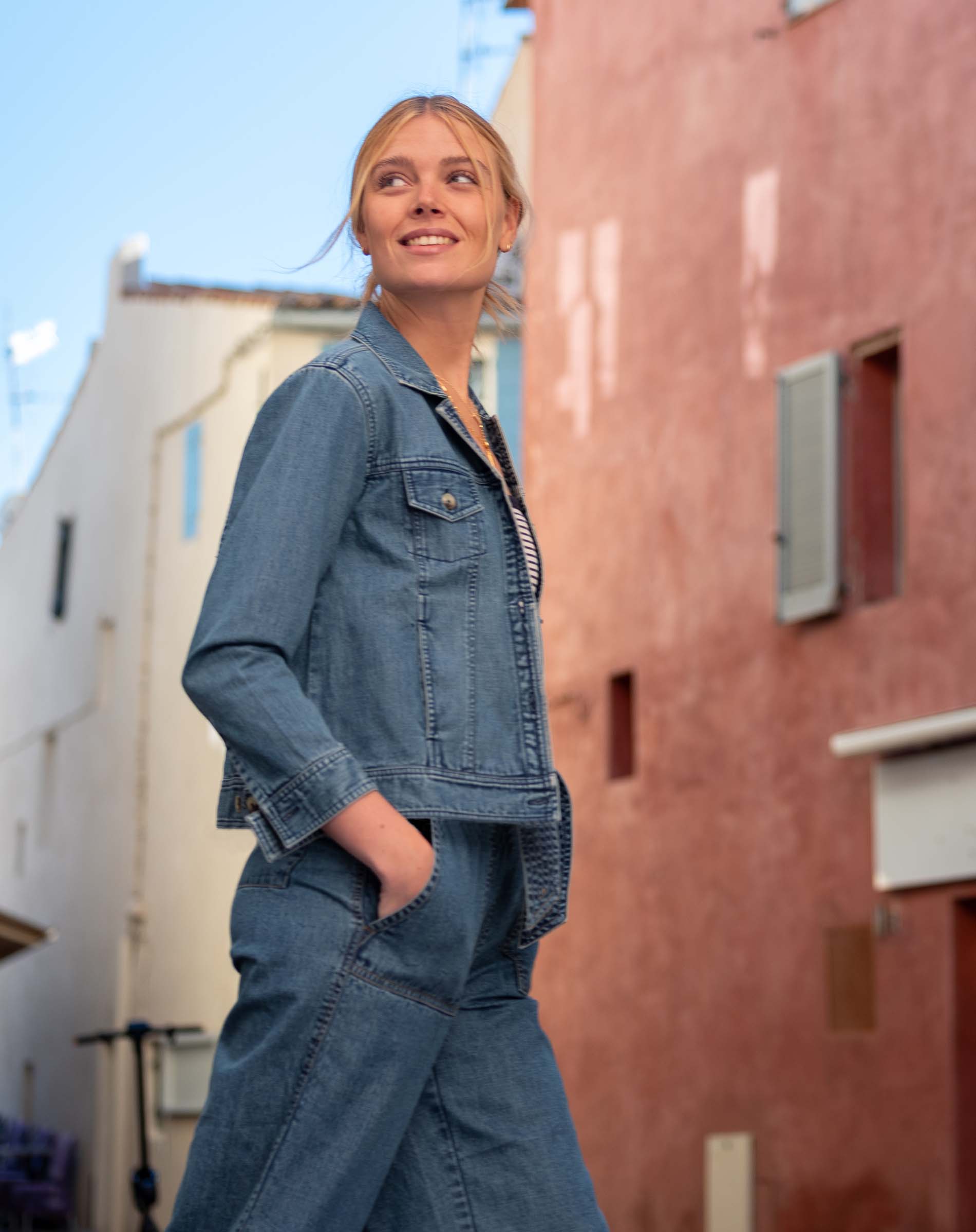 Woman wearing a denim outfit standing in an urban alleyway.