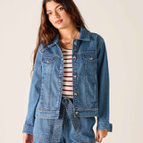 Woman wearing a denim jacket and striped shirt against a plain background