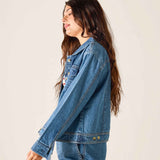 Person wearing a blue denim jacket and pants against a plain background