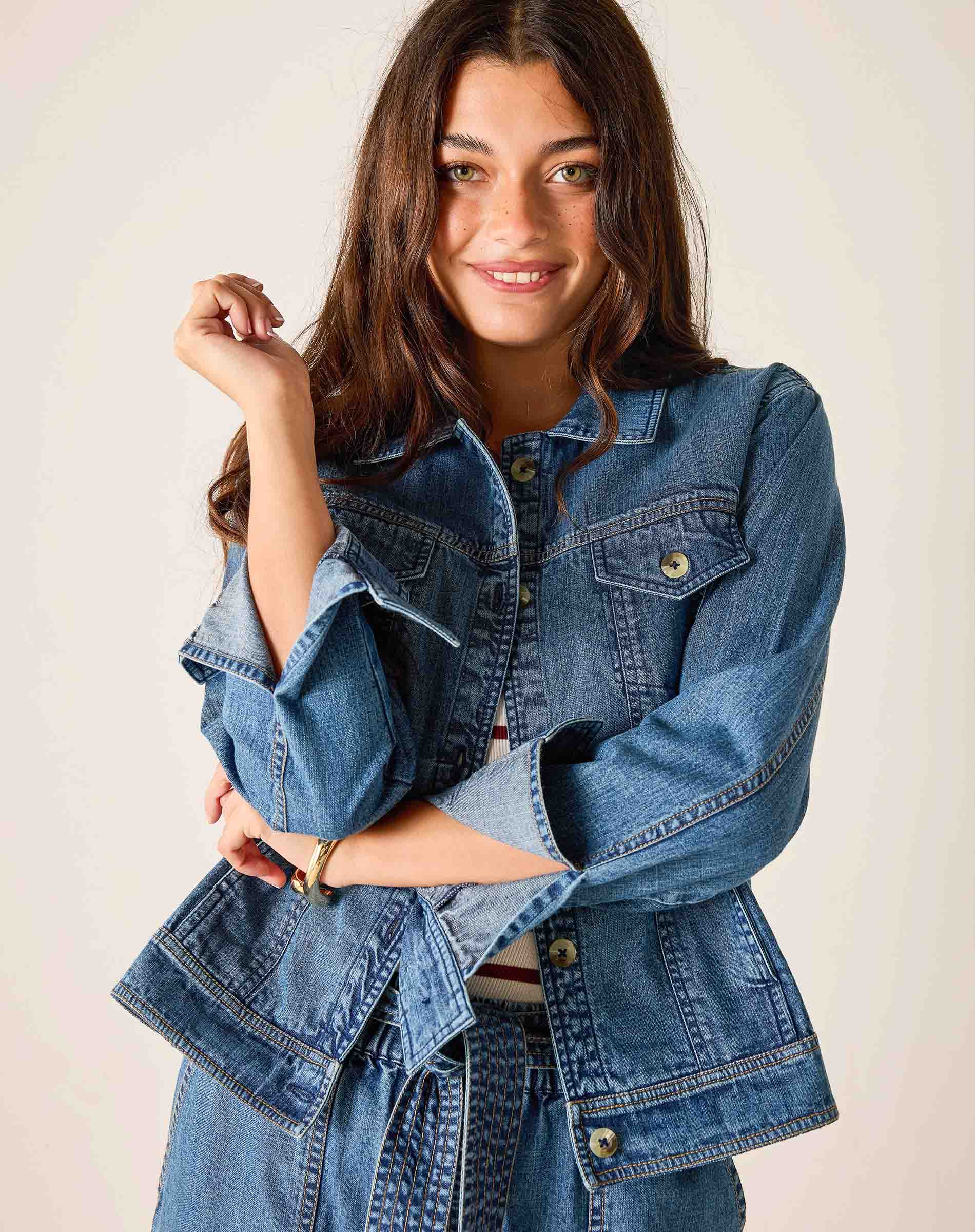 Woman wearing a blue denim jacket against a plain background