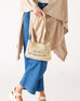 woman holding sun chaser straw pochette in hand with jeans on