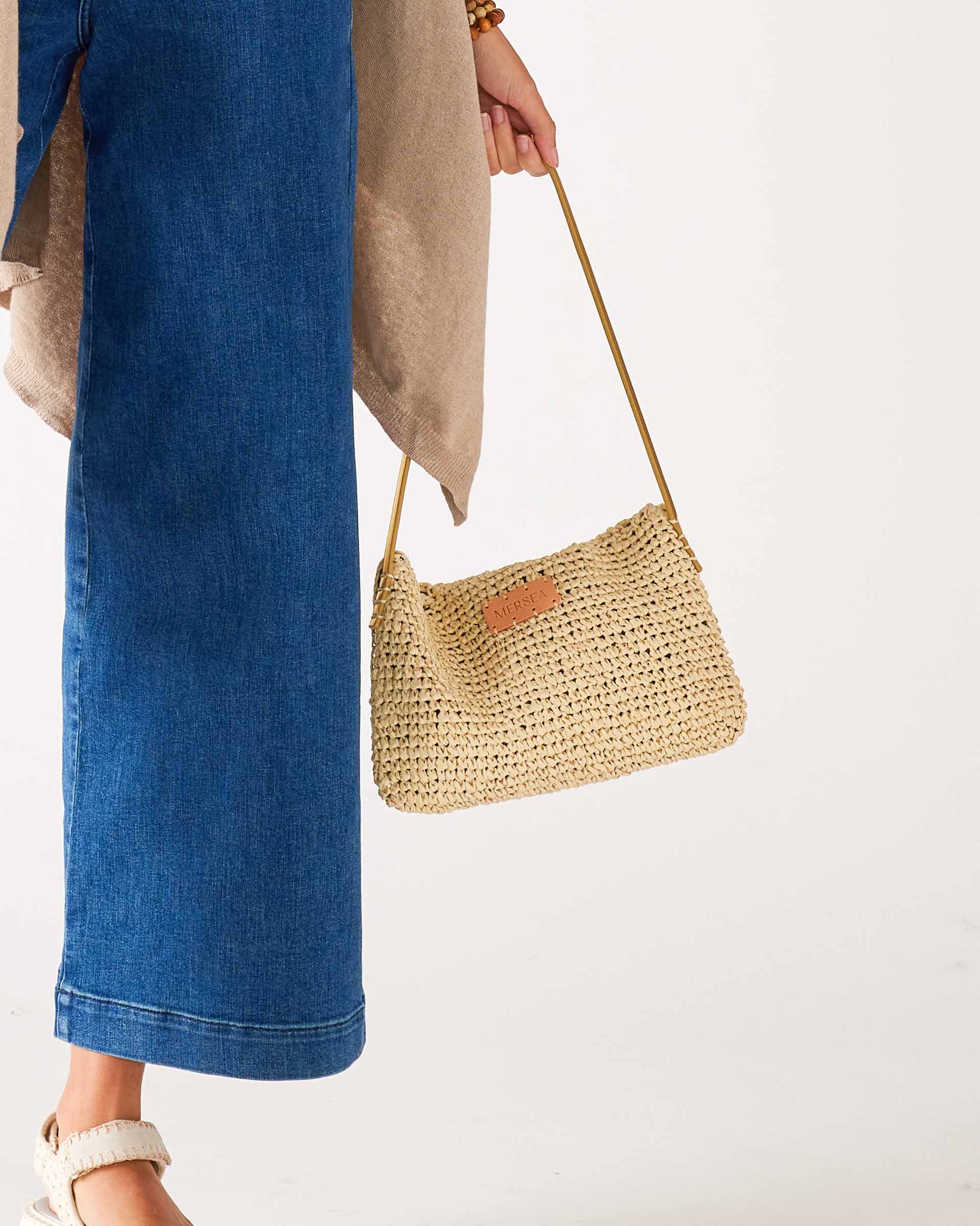 close up image of woman holding sun chaser straw pochette