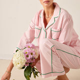 Woman in pink pajama set holding a bouquet of flowers on a neutral background