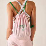 Person wearing a pink drawstring bag with green straps on a plain background