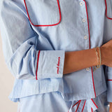 Light blue pajama set with red piping worn by a person, on a neutral background.